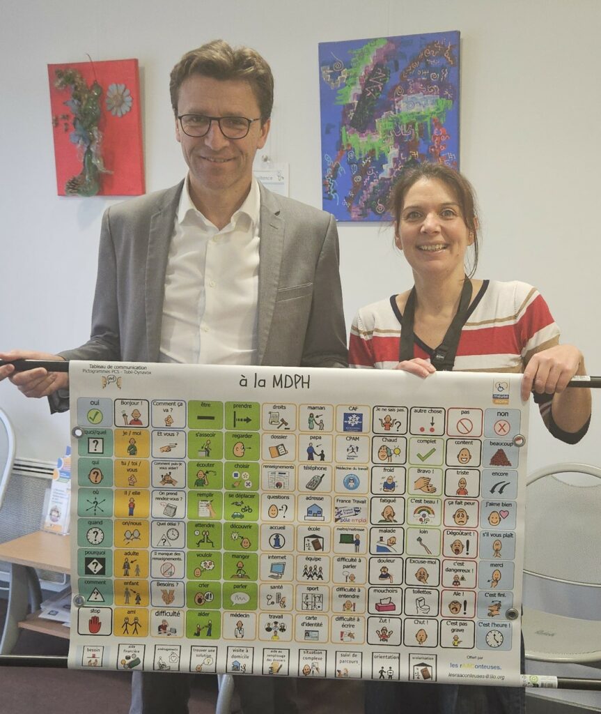 Monsieur Dumont, président du Conseil départemental de la Meuse, et Aline Ledoux la rAAConteuse, prennent la pose derrière un tableau de communication "à la MDPH"